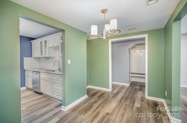 kitchen with white cabinetry, sink, stainless steel dishwasher, light stone countertops, and light hardwood / wood-style flooring