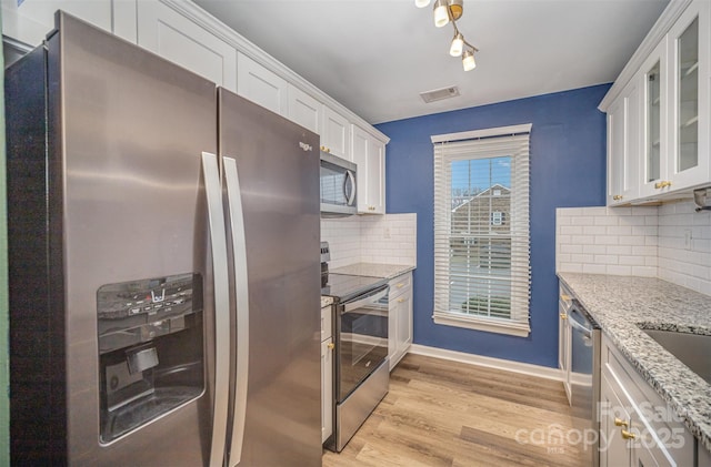 kitchen featuring stainless steel appliances, white cabinets, light stone counters, and light hardwood / wood-style flooring