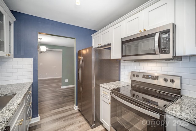 kitchen featuring appliances with stainless steel finishes, white cabinets, and light stone counters