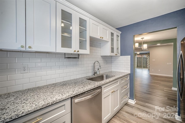 kitchen featuring white cabinetry, light stone countertops, sink, and stainless steel dishwasher