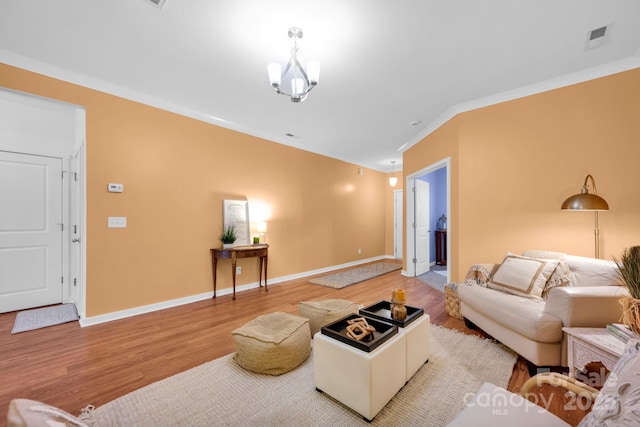 living room with ornamental molding, a chandelier, and light hardwood / wood-style flooring