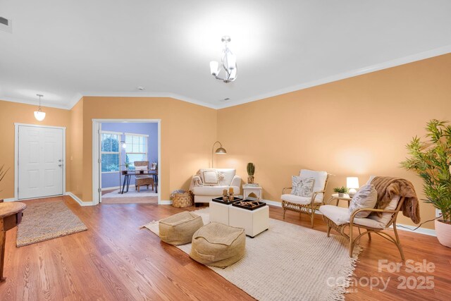 sitting room featuring hardwood / wood-style flooring, ornamental molding, and a chandelier