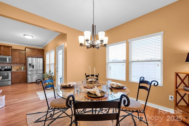 dining space with a notable chandelier, ornamental molding, a wealth of natural light, and light wood-type flooring