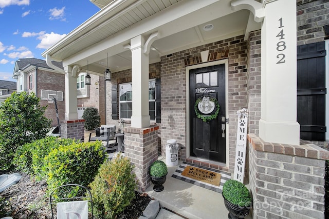 doorway to property with covered porch and brick siding