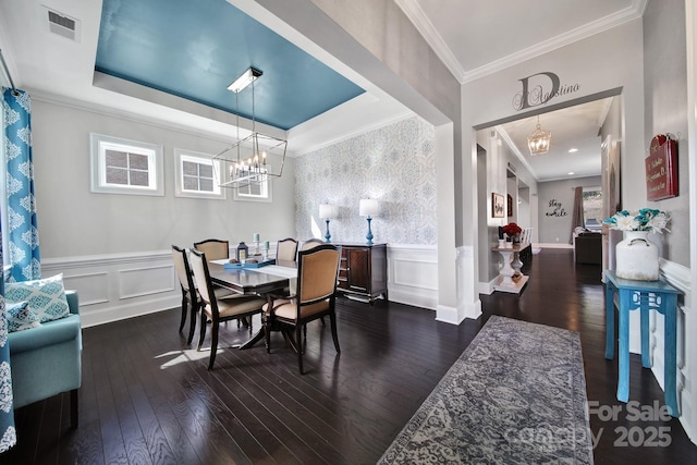 dining space featuring crown molding, dark wood finished floors, visible vents, a raised ceiling, and an inviting chandelier