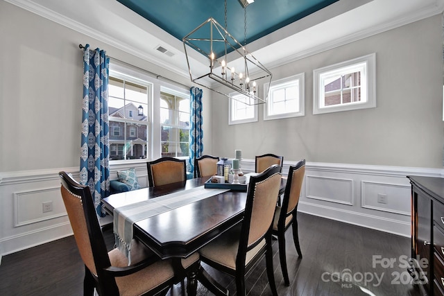 dining area with a wainscoted wall, dark wood-style flooring, visible vents, and crown molding