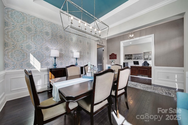 dining room with crown molding, dark wood-style flooring, a wainscoted wall, and a decorative wall