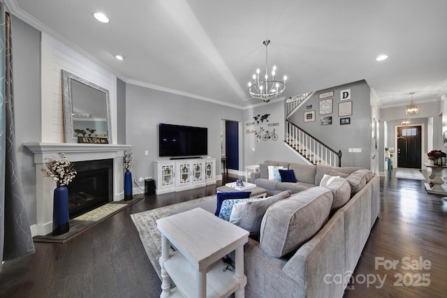 living room with a fireplace, stairway, dark wood-style floors, an inviting chandelier, and crown molding