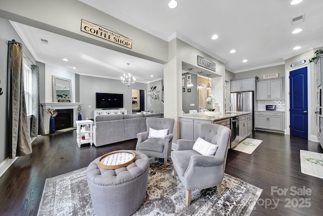 living room featuring dark wood-style floors, a fireplace, visible vents, and crown molding