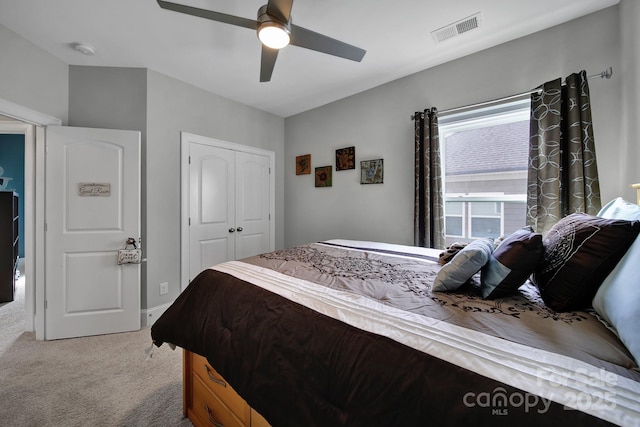 bedroom with ceiling fan, visible vents, a closet, and light colored carpet