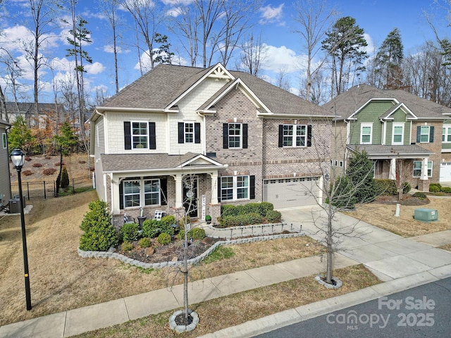 view of front of home featuring a garage, brick siding, fence, driveway, and roof with shingles