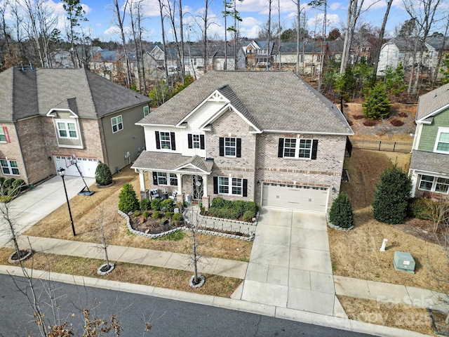 traditional home featuring brick siding, a shingled roof, concrete driveway, a garage, and a residential view