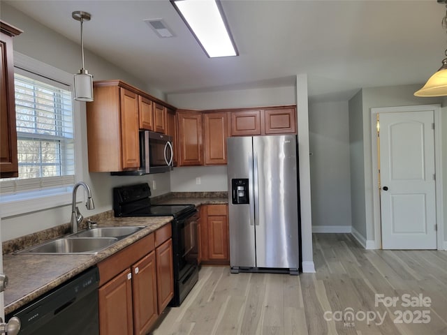 kitchen with sink, black appliances, hanging light fixtures, and light hardwood / wood-style flooring