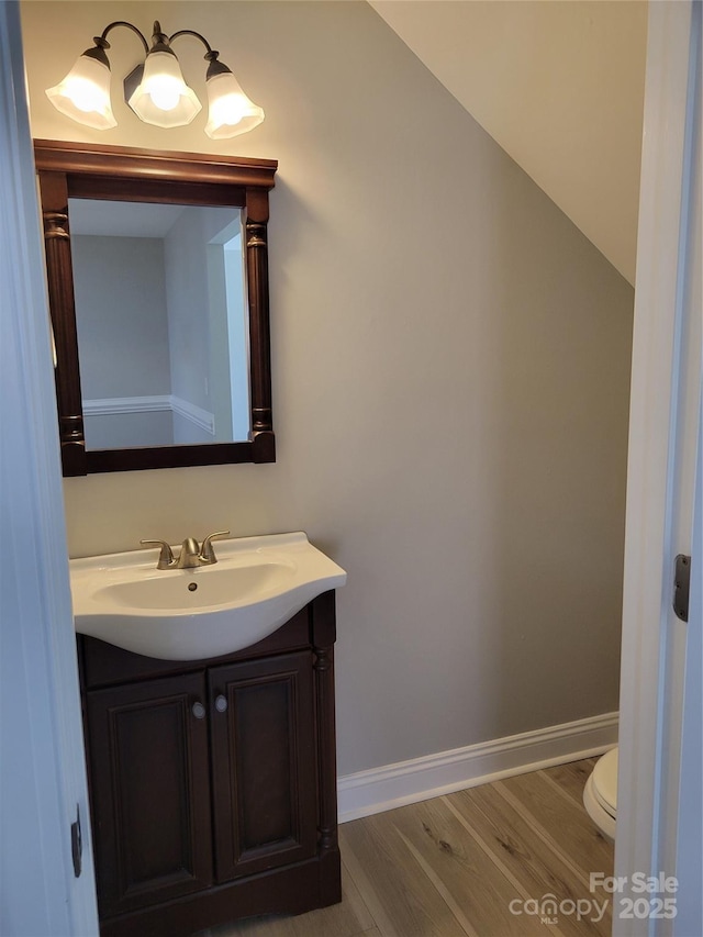 bathroom with toilet, vanity, and wood-type flooring