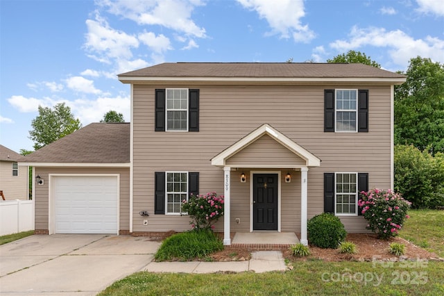 colonial inspired home with a garage, fence, and concrete driveway