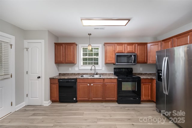 kitchen with brown cabinets, a sink, light wood-type flooring, visible vents, and black appliances