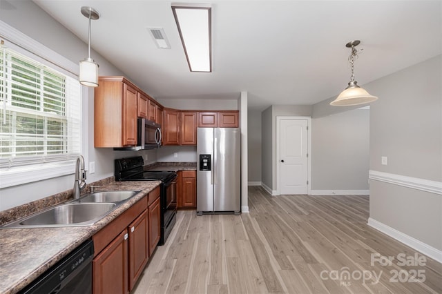 kitchen featuring visible vents, pendant lighting, light wood-type flooring, a sink, and black appliances