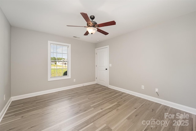 spare room with light wood-style floors, baseboards, ceiling fan, and visible vents