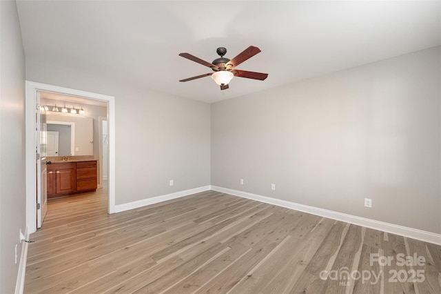unfurnished bedroom featuring light wood-style floors, connected bathroom, baseboards, and ceiling fan