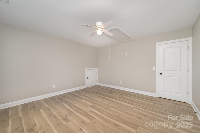 spare room with light wood-style floors, attic access, baseboards, and a ceiling fan