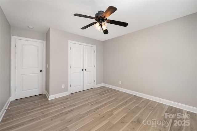unfurnished bedroom with baseboards, light wood finished floors, ceiling fan, and a closet