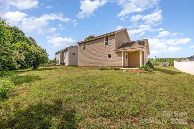 rear view of property with a lawn and fence