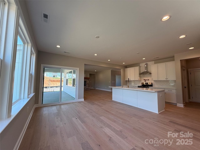 kitchen featuring visible vents, decorative backsplash, baseboards, wall chimney exhaust hood, and stainless steel range oven