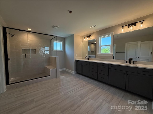bathroom with visible vents, a sink, plenty of natural light, and a tile shower