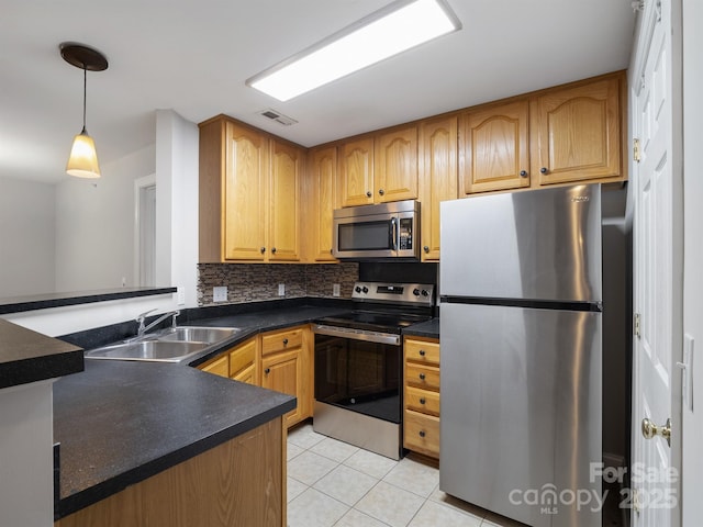 kitchen with stainless steel appliances, dark countertops, decorative backsplash, light tile patterned flooring, and a sink