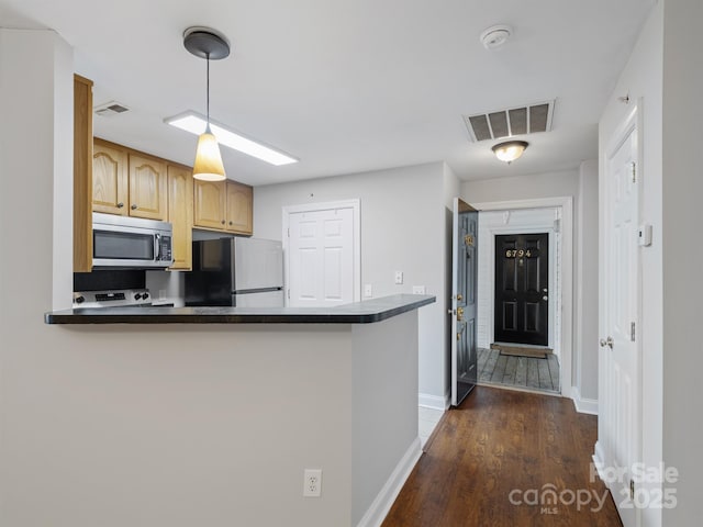 kitchen featuring dark countertops, visible vents, stainless steel microwave, and refrigerator