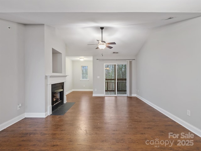 unfurnished living room featuring a fireplace with flush hearth, visible vents, vaulted ceiling, and dark wood-type flooring