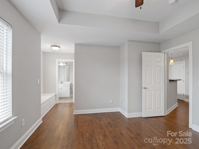 unfurnished bedroom featuring dark wood-type flooring, a ceiling fan, and baseboards