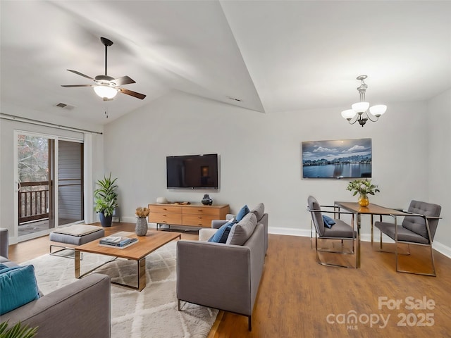 living room featuring visible vents, vaulted ceiling, baseboards, and wood finished floors