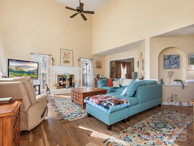 living room featuring hardwood / wood-style flooring, ceiling fan, and a high ceiling