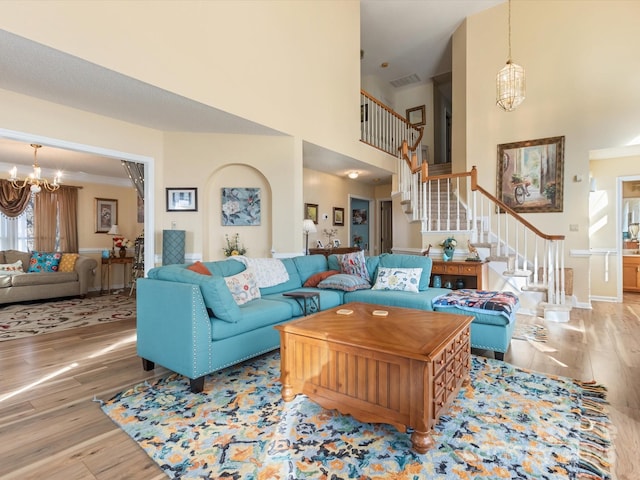 living room featuring hardwood / wood-style flooring, crown molding, a high ceiling, and a notable chandelier