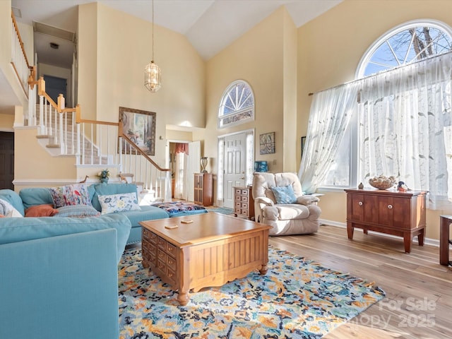 living room with high vaulted ceiling, a healthy amount of sunlight, and light hardwood / wood-style floors