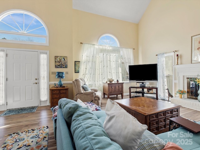 living room with hardwood / wood-style floors, a fireplace, and high vaulted ceiling