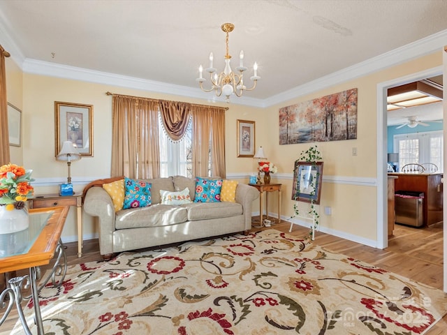 living room featuring ceiling fan with notable chandelier, ornamental molding, and light hardwood / wood-style floors