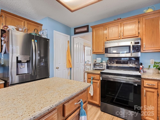 kitchen with light stone counters, light hardwood / wood-style flooring, and stainless steel appliances