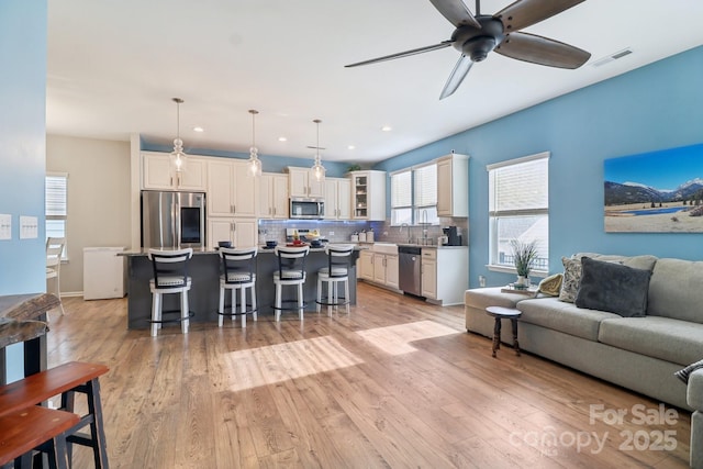 living room with ceiling fan, sink, and light hardwood / wood-style floors