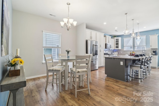 kitchen with hanging light fixtures, stainless steel appliances, light stone countertops, white cabinets, and a kitchen island