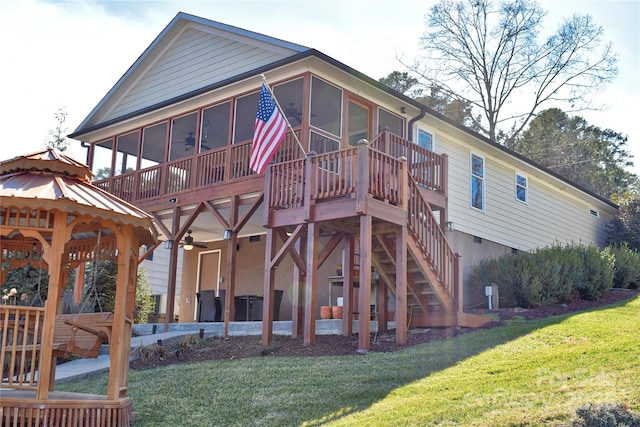 rear view of property with a patio, stairway, a ceiling fan, a sunroom, and a lawn