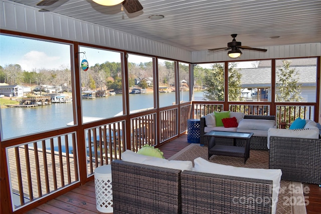 sunroom with plenty of natural light, a ceiling fan, and a water view