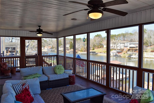 sunroom with ceiling fan and a water view