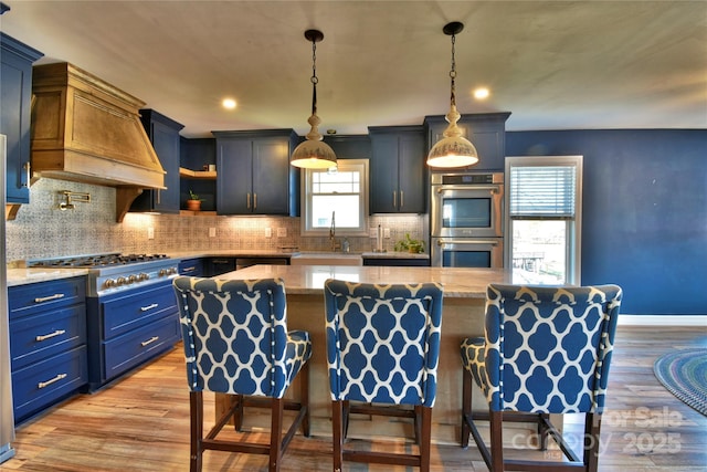 kitchen with a sink, stainless steel appliances, light wood-type flooring, and custom exhaust hood