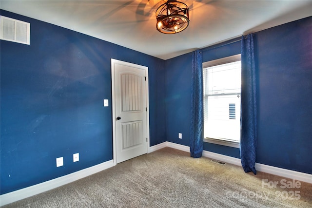 carpeted spare room featuring baseboards and visible vents