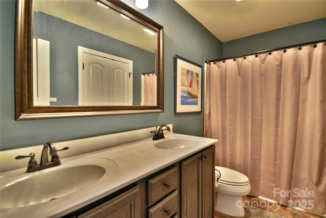 full bath with a sink, curtained shower, toilet, and double vanity