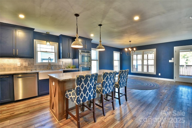 kitchen featuring a kitchen bar, tasteful backsplash, light wood-type flooring, and appliances with stainless steel finishes