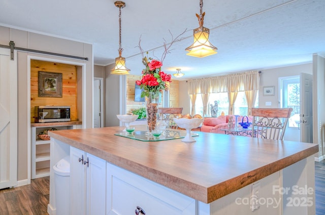 kitchen featuring decorative light fixtures, a center island, dark hardwood / wood-style flooring, a barn door, and white cabinets