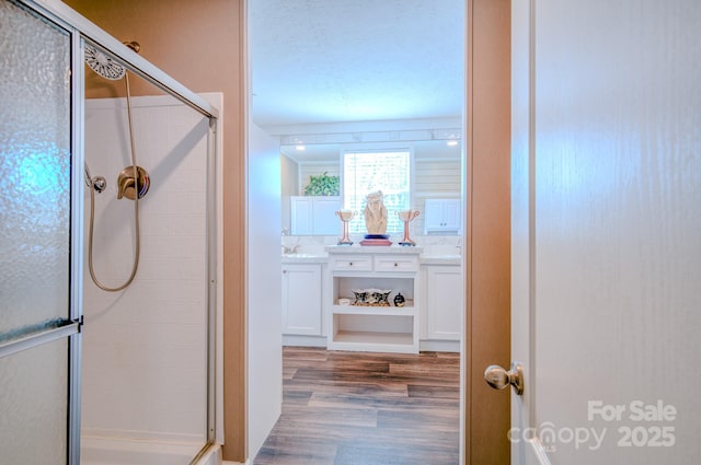 bathroom featuring vanity, an enclosed shower, hardwood / wood-style floors, and a textured ceiling